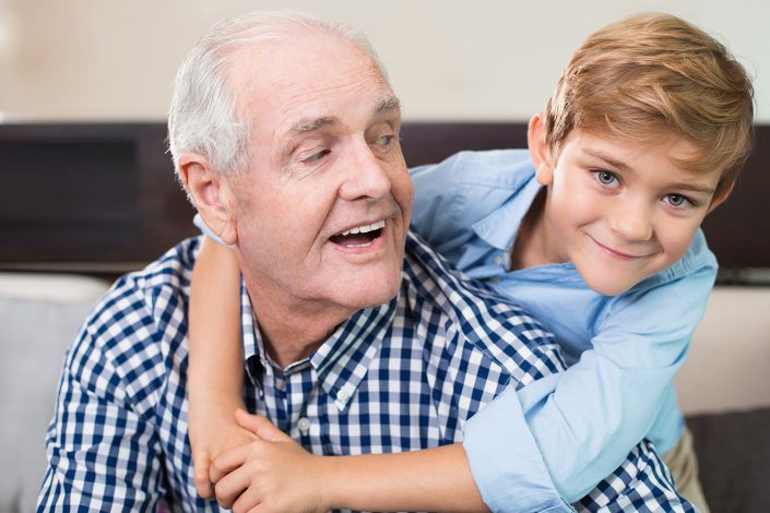 Happy little boy embracing senior grandfather